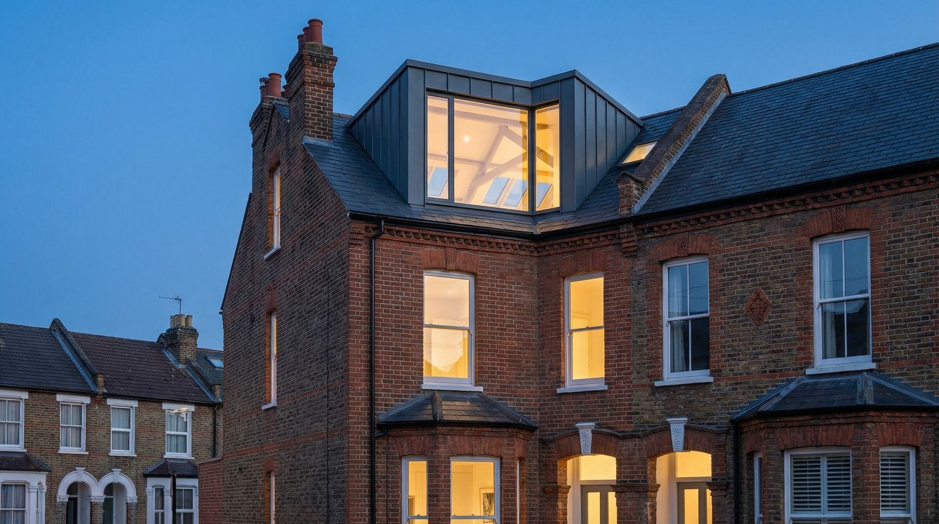 Row of brick homes with new extensions at dusk